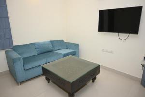 sala de estar con sofá azul y TV en ownstay chhatarpur en Nueva Delhi