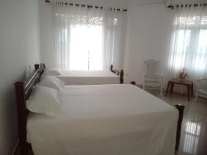 sypialnia z 2 białymi łóżkami i oknem w obiekcie Ananthaya -the infinity w mieście Kalutara