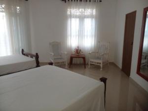 a bedroom with two beds and two chairs and windows at Ananthaya -the infinity in Kalutara