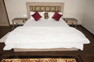 a bedroom with a large white bed with red pillows at ownstay chhatarpur in New Delhi