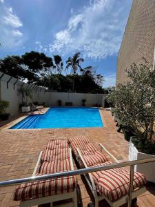 a swimming pool with two lounge chairs next to a building at 503 Hawaan View in Durban