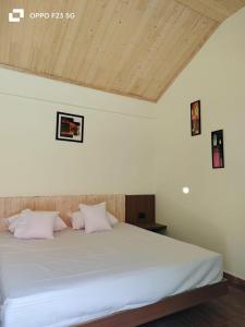 un letto con lenzuola e cuscini bianchi in una stanza di Shivay Homestay a Pithorāgarh