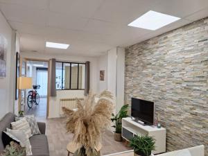 - un salon avec une télévision et un mur en briques dans l'établissement Chez Nous, à Cherbourg en Cotentin