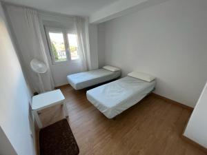 Cette petite chambre comprend 2 lits et une fenêtre. dans l'établissement Precioso apartamento cerca de la playa en Villajoyosa, à La Vila Joiosa