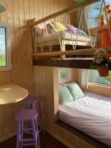 een stapelbed in een hut met 2 paarse krukken bij Tiny house Smûk in Tietjerk