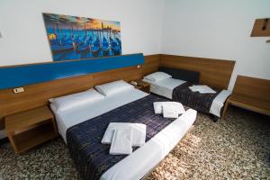 Dos camas en una habitación de hotel con toallas. en BlueColors Hotel ex Hotel Lucy, en Campalto
