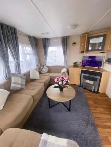 布萊特靈西的住宿－Coastal caravan retreat，客厅配有沙发和鲜花桌