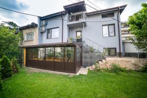 Biały dom z brązowymi drzwiami i ogródkiem w obiekcie Къща за гости Алекс w mieście Karłowo