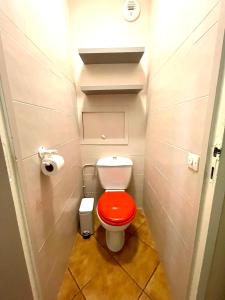 aseo con asiento rojo en un baño pequeño en Chambre Privée en colocation dans un appartement Vaulx en Velin Centre en Vaulx-en-Velin