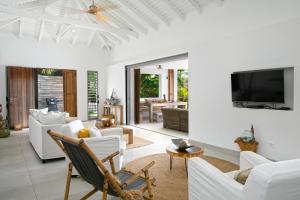 a living room with white furniture and a flat screen tv at VILLA BE in Cul de Sac