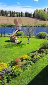 einen Garten mit einer Brücke über einen Fluss mit Blumen in der Unterkunft Dolina Miodu - Kaszuby, Sauna, Gorąca Balia in Borowina