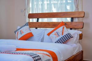 ein Bett mit orangefarbenen und weißen Kissen darauf in der Unterkunft Greenview apartments nanyuki in Nanyuki