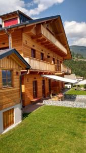 a large wooden house with a lawn in front of it at dolomit24 | design apARTments in Sillian