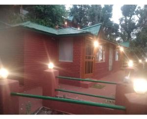a small red brick house with lights on it at Trinetra Orchards in Mukteswar