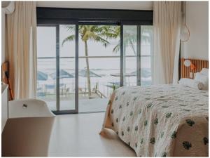 a bedroom with a bed and a view of the ocean at Chez Louise et Louis Pé na Areia in Juquei