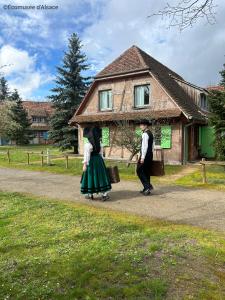 Due persone che camminano lungo una strada davanti a una casa di Les Loges de l'Ecomusée D'Alsace a Ungersheim