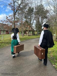 due persone che camminano per strada con le valigie di Les Loges de l'Ecomusée D'Alsace a Ungersheim