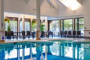 a swimming pool with chairs and tables in a building at Coylumbridge Hotel in Aviemore