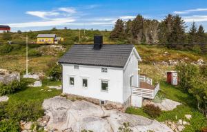 una pequeña casa blanca sobre una roca en Cozy Home In Norddyry With Kitchen en Sætra