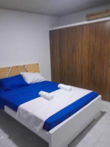 a bedroom with a blue and white bed with a wooden cabinet at Hanna's House. in Villavicencio