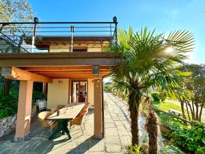 una casa con una mesa de madera y una palmera en Villa Riflessi - Manerba del Garda - by tourquoisevea, en Manerba del Garda
