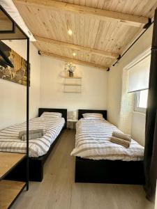 Dos camas en una habitación con techos de madera. en Cantinho da Verdade, en Odiáxere