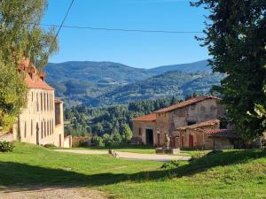 un grupo de edificios con montañas en el fondo en L'Eclat de menthe, en Augerolles