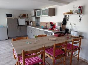 cocina con mesa de madera y sillas acolchadas de color rosa en L'Eclat de menthe, en Augerolles