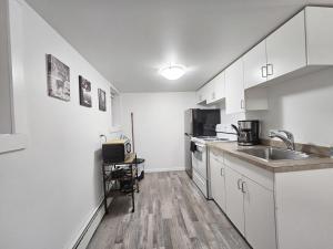 a kitchen with white cabinets and a sink and a microwave at Affordable Double Bed Parking Downtown A plus WiFi in Moose Jaw