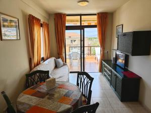 een woonkamer met een tafel, een bank en een televisie bij 1-bedroom apartment with big terrace and ocean view in Los Cristianos in Los Cristianos