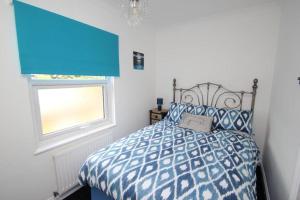 a bedroom with a bed with a blue comforter and a window at The Zen Den in Southend-on-Sea