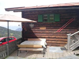 a wooden cabin with a bench and an umbrella at Almhütte Andrea in Wildschönau
