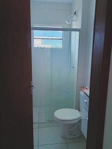 a white bathroom with a toilet and a window at Quarto Cambirela in Palhoça