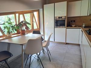 cocina con armarios blancos, mesa y sillas en Mediterrán apartman en Pécs