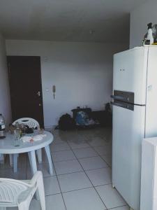 a kitchen with a table and a white refrigerator at Quarto Cambirela in Palhoça