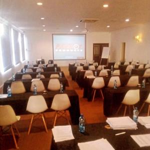 una sala conferenze con tavoli, sedie e schermo di Sapphire Hotel Halevy Heritage a Bloemfontein