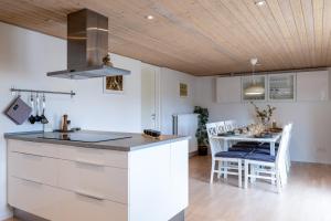 a kitchen with white cabinets and a table with chairs at Cozy Apartment Stevns in Store Heddinge
