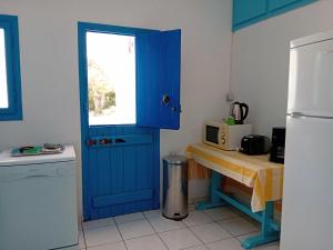 a kitchen with a blue door and a table with a microwave at Residence Gerani in Agios Nikolaos