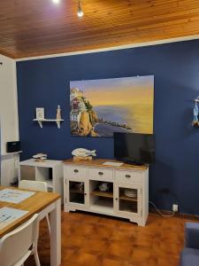 Habitación con pared azul, TV y mesa. en Casa LA MARINA, en Manarola