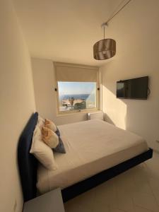 a bedroom with a bed with a window and a television at Puglia Dreaming seaview apartment in Polignano a Mare