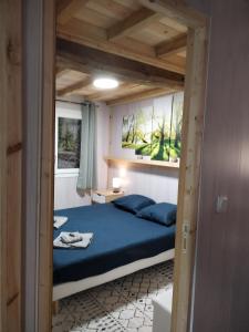 um quarto com uma cama com lençóis azuis e tectos em madeira em Appartement gîte du Gardoir em Boresse-et-Martron
