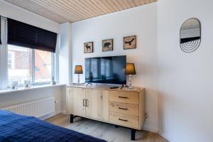 um quarto com uma televisão numa cómoda com uma cama em Cozy Apartment Stevns em Store Heddinge