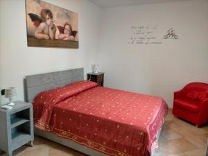 um quarto com uma cama e uma cadeira vermelha em CASA ELGA em Borgo a Buggiano