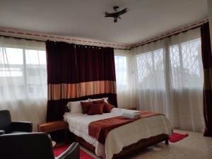 a bedroom with a bed with curtains and windows at Résidence Tianay in Antananarivo