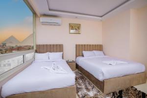 um quarto de hotel com duas camas e uma janela em Mak Pyramids View em Cairo