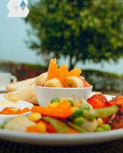 une assiette avec un bol de légumes sur une table dans l'établissement Five Mounts Hotel And Restaurant, à Multan