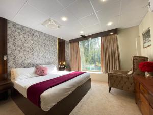 a bedroom with a bed and a chair and a window at The Life Style Lodges opp Centaurus Mall in Islamabad