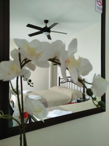um espelho com uma cama num quarto com flores brancas em Paradise Garden Paros em Piso Livadi