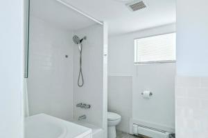 La salle de bains blanche est pourvue d'une douche et de toilettes. dans l'établissement Luxury Lower Ground 2BD - Manhattan Beach, à Brooklyn