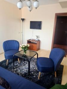 uma sala de estar com duas cadeiras azuis e uma mesa de vidro em Apart Hotel Sutoris em Bochnia